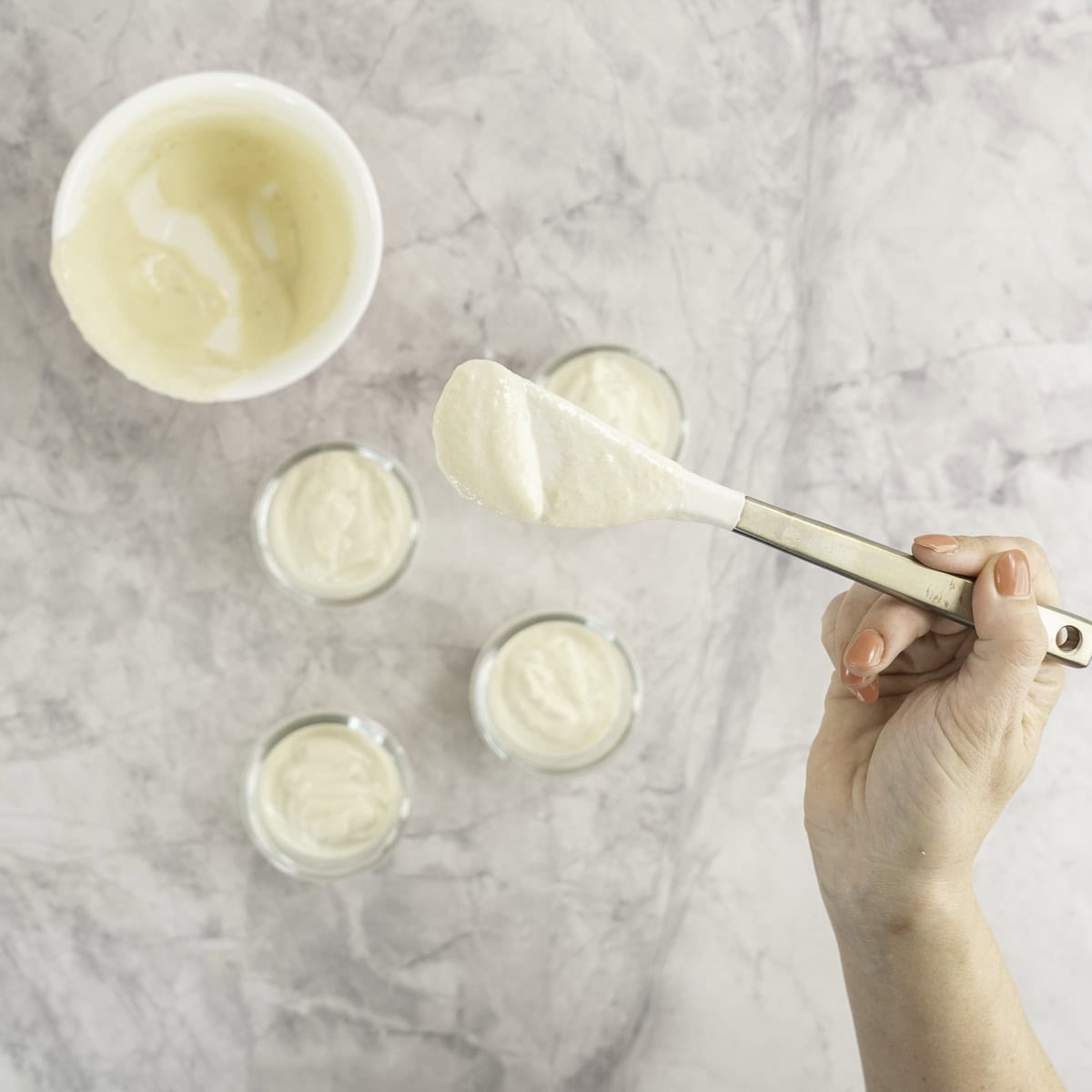Banana yogurt being portioned into small glass cups/bowls.