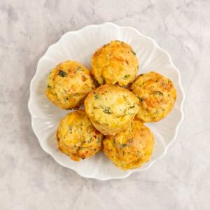 Six muffins packed with vegetables on a white plate.