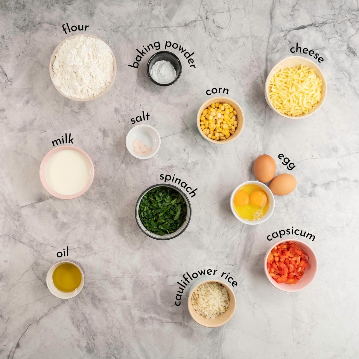 Ingredients for veggie muffins on bench top with text overlay.