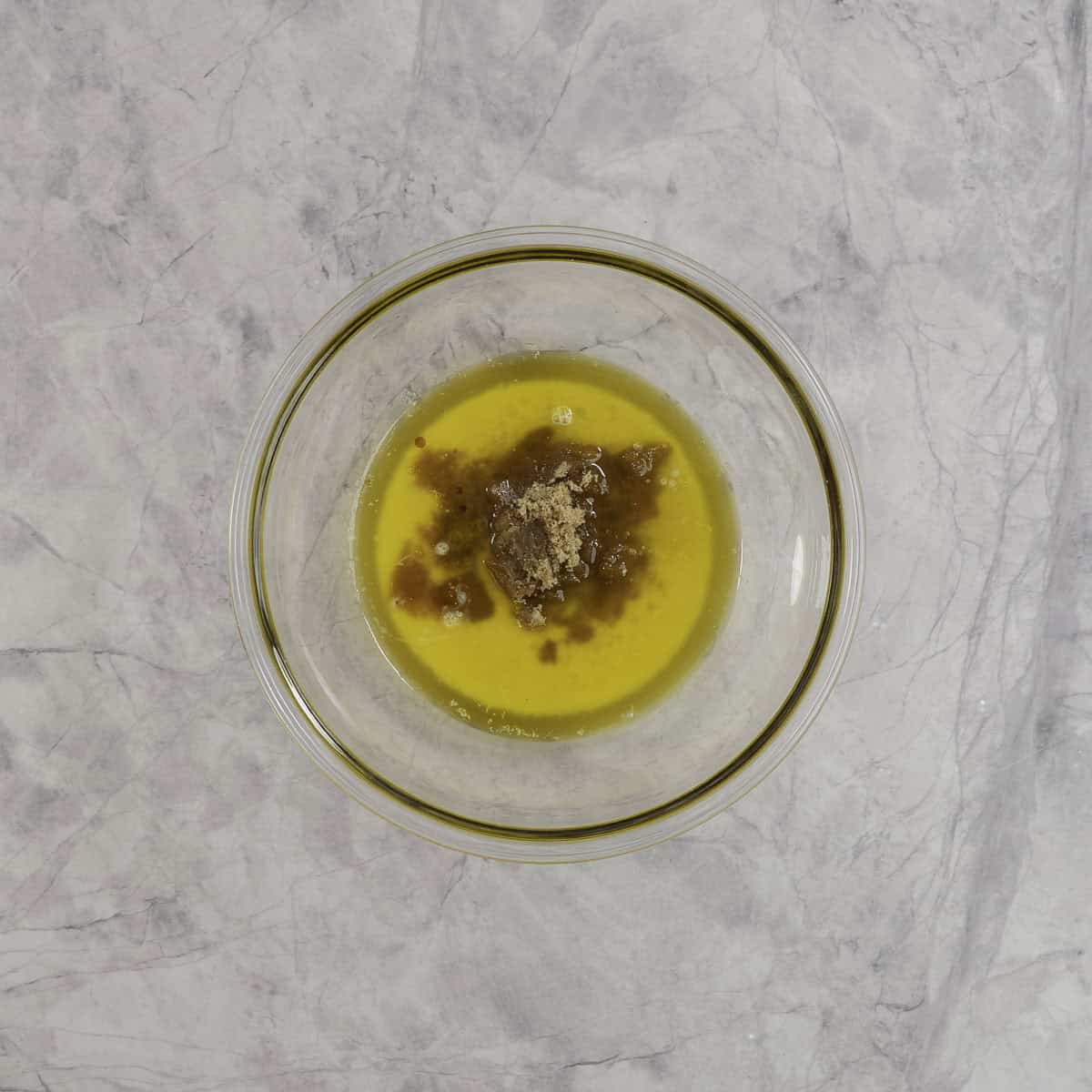 Melted butter and brown sugar in a large glass bowl on benchtop.
