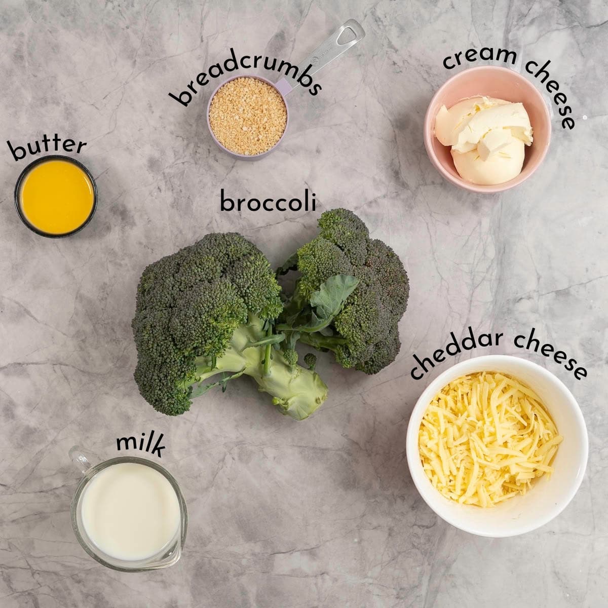 Ingredients for broccoli cheese casserole on marble benchtop with txt overlay.