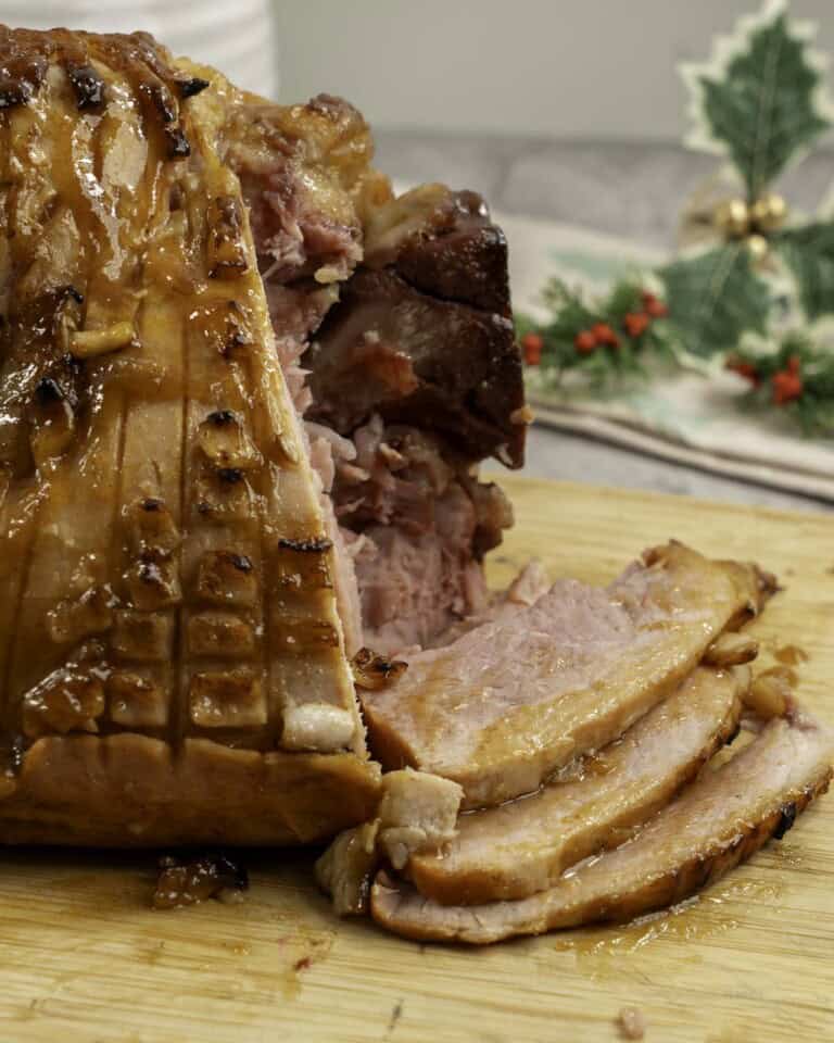 Golden glossy ham, three pieces of ham slice onto wooden chopping board.