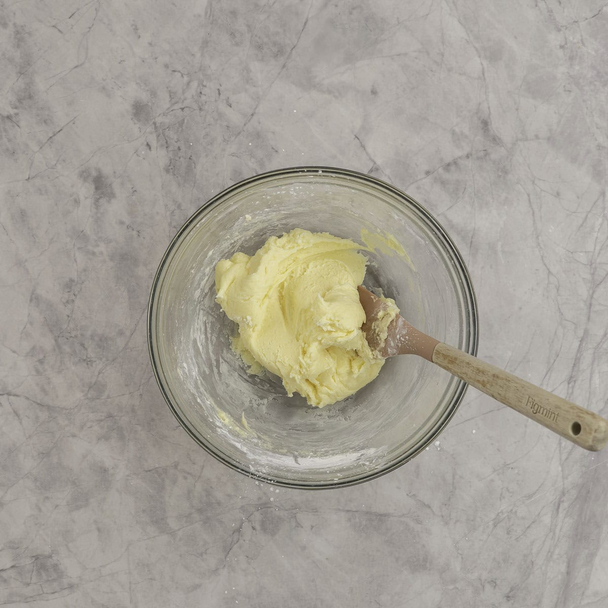 Batter for mint melt aways in a large glass bowl on marble benchtop with spatula inside,