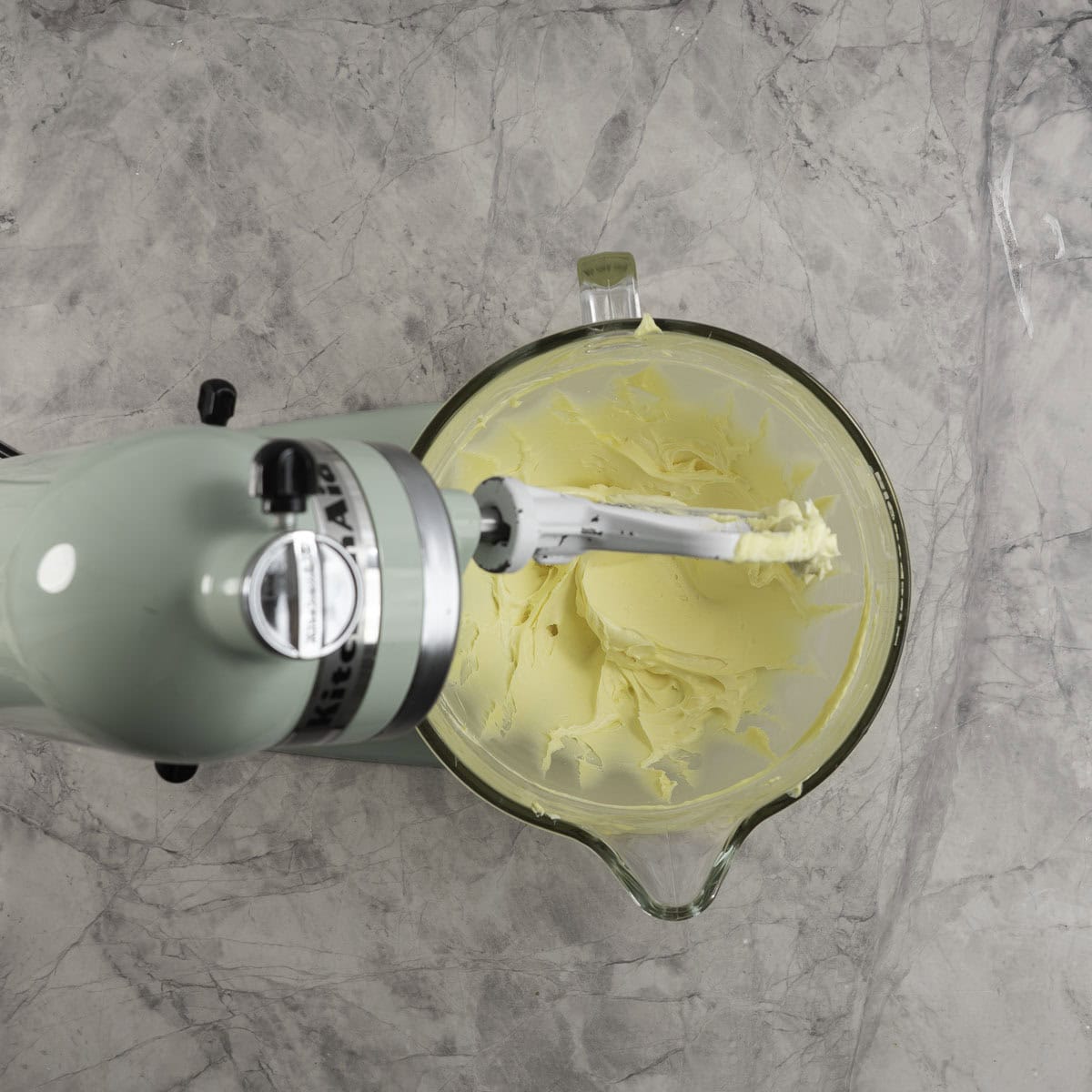 Creamed butter and icing sugar in a stand mixer with a glass bowl.